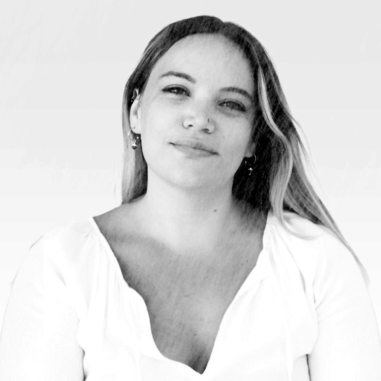 A black-and-white photo of a smiling woman with long hair, a nose ring, and earrings.