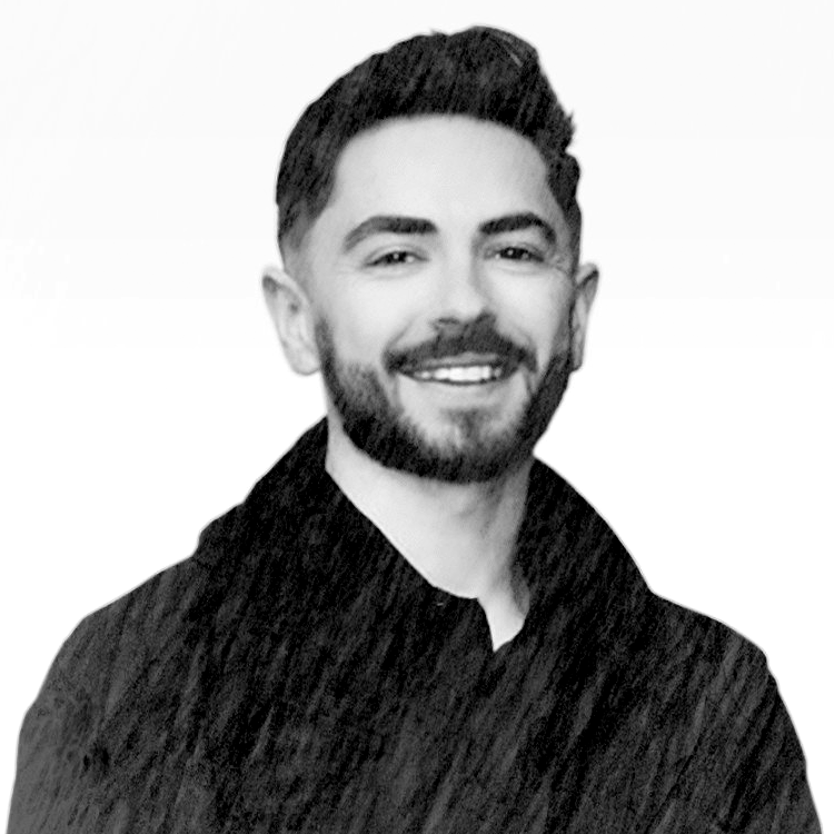 Black and white portrait of a smiling man with a beard, wearing a black shirt.