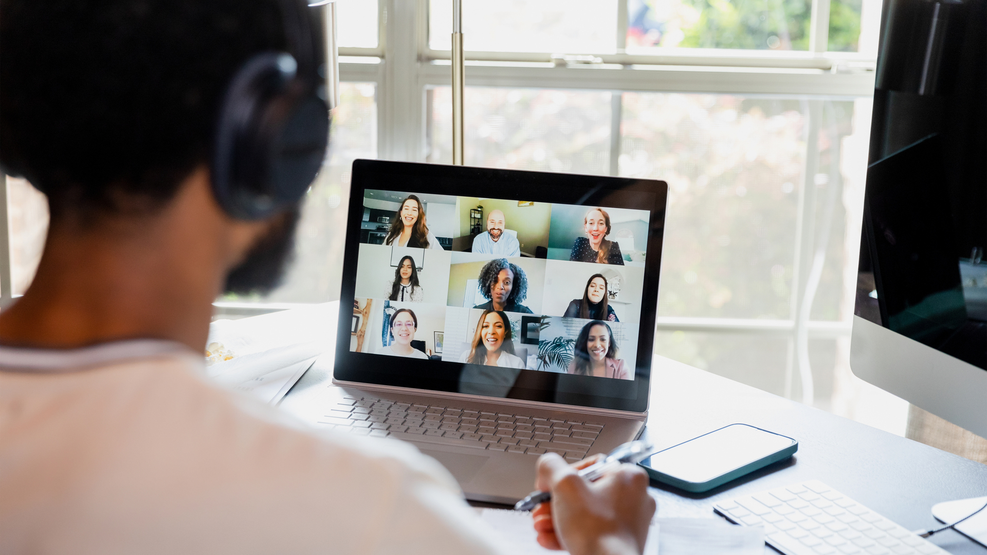 A person attending a virtual meeting with multiple participants on their laptop screen.