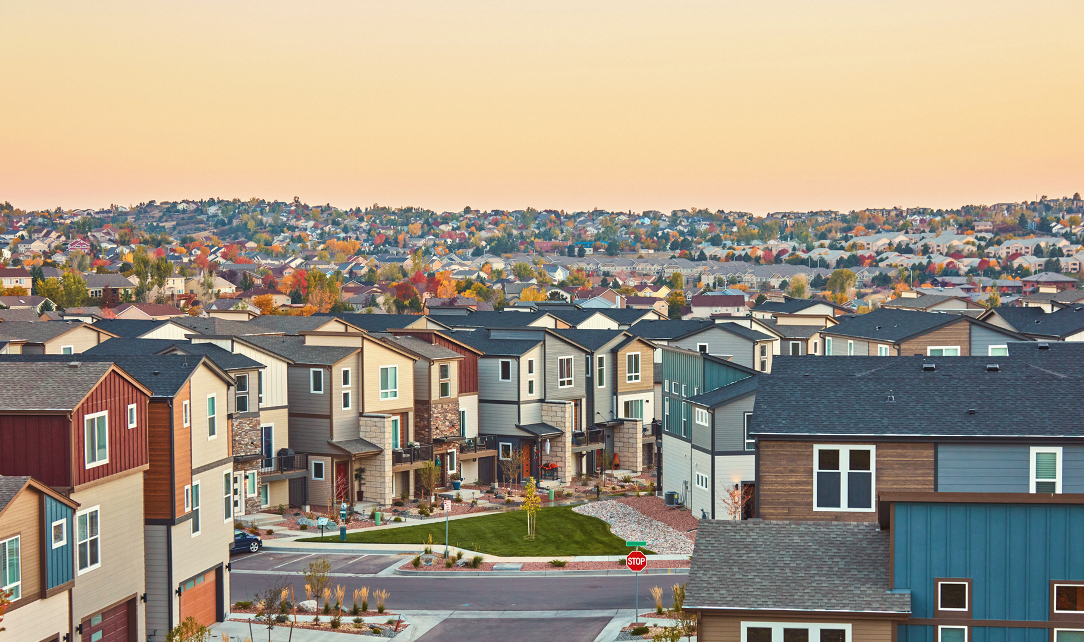 A suburb with rows of colorful houses stretching into the distance during twilight.