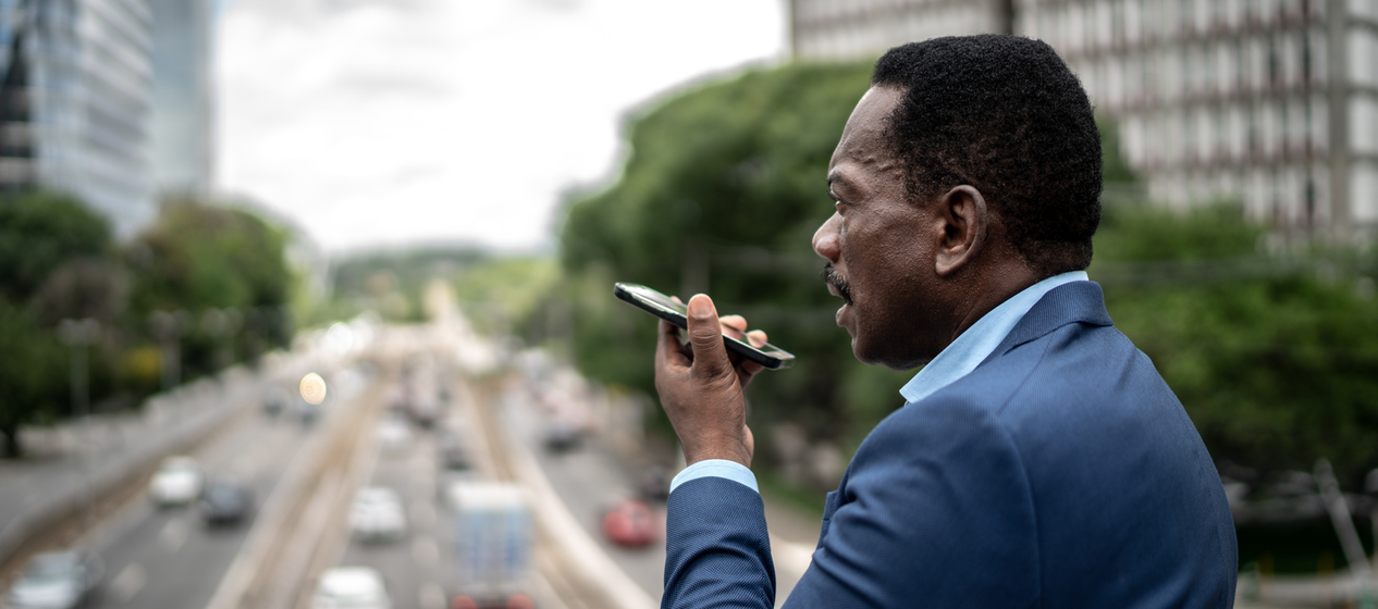 Man in suit using phone with city traffic in background.