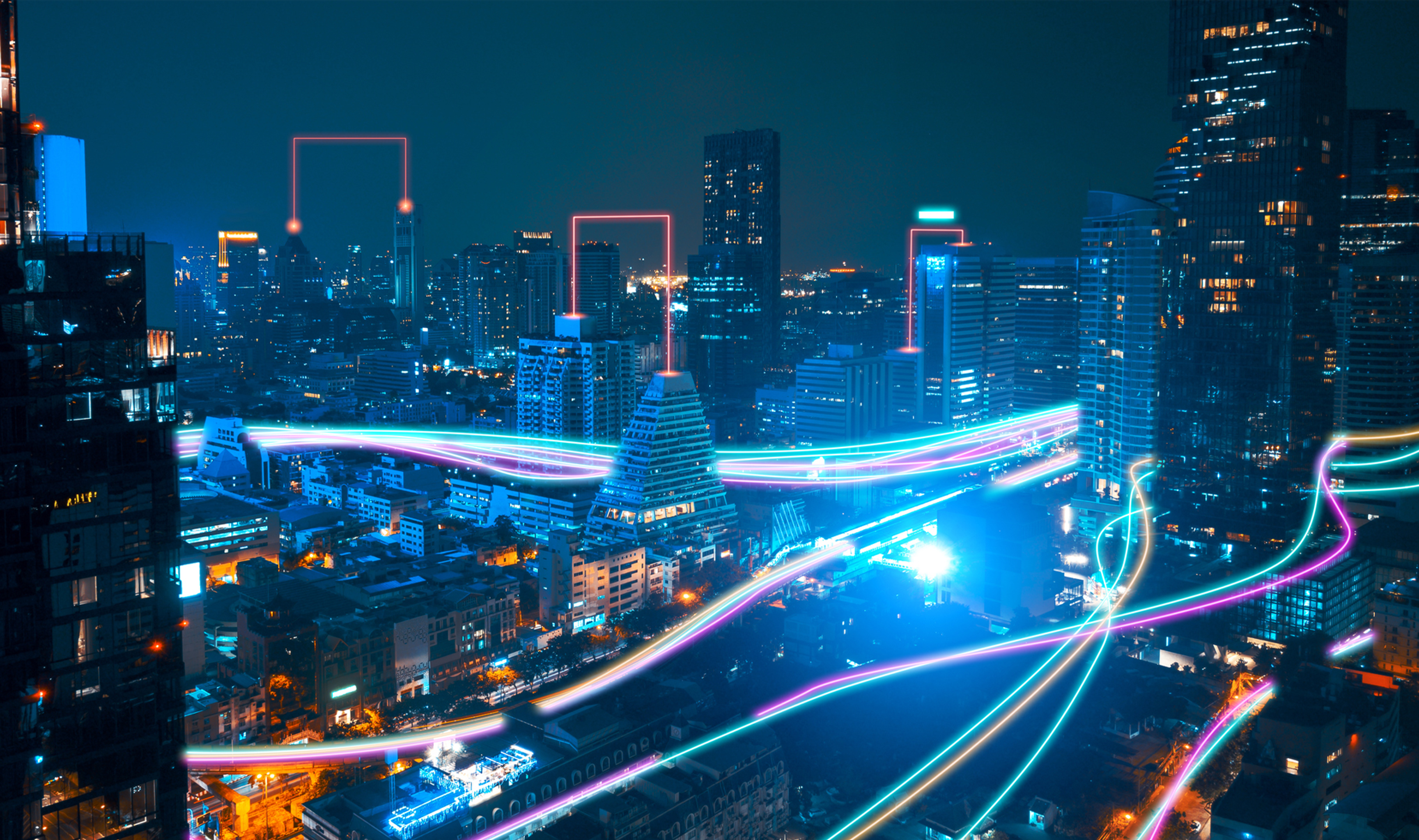 A night cityscape with neon lights highlighting building contours and vibrant streaks suggesting futuristic transportation paths.