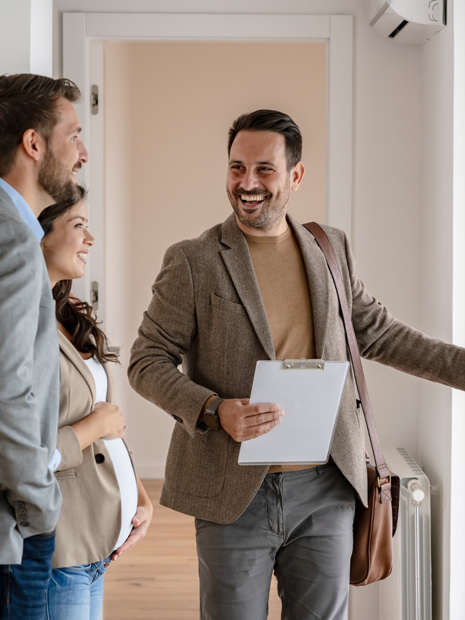 Three people sharing a cheerful moment; one person is holding a clipboard, possibly a real estate situation.